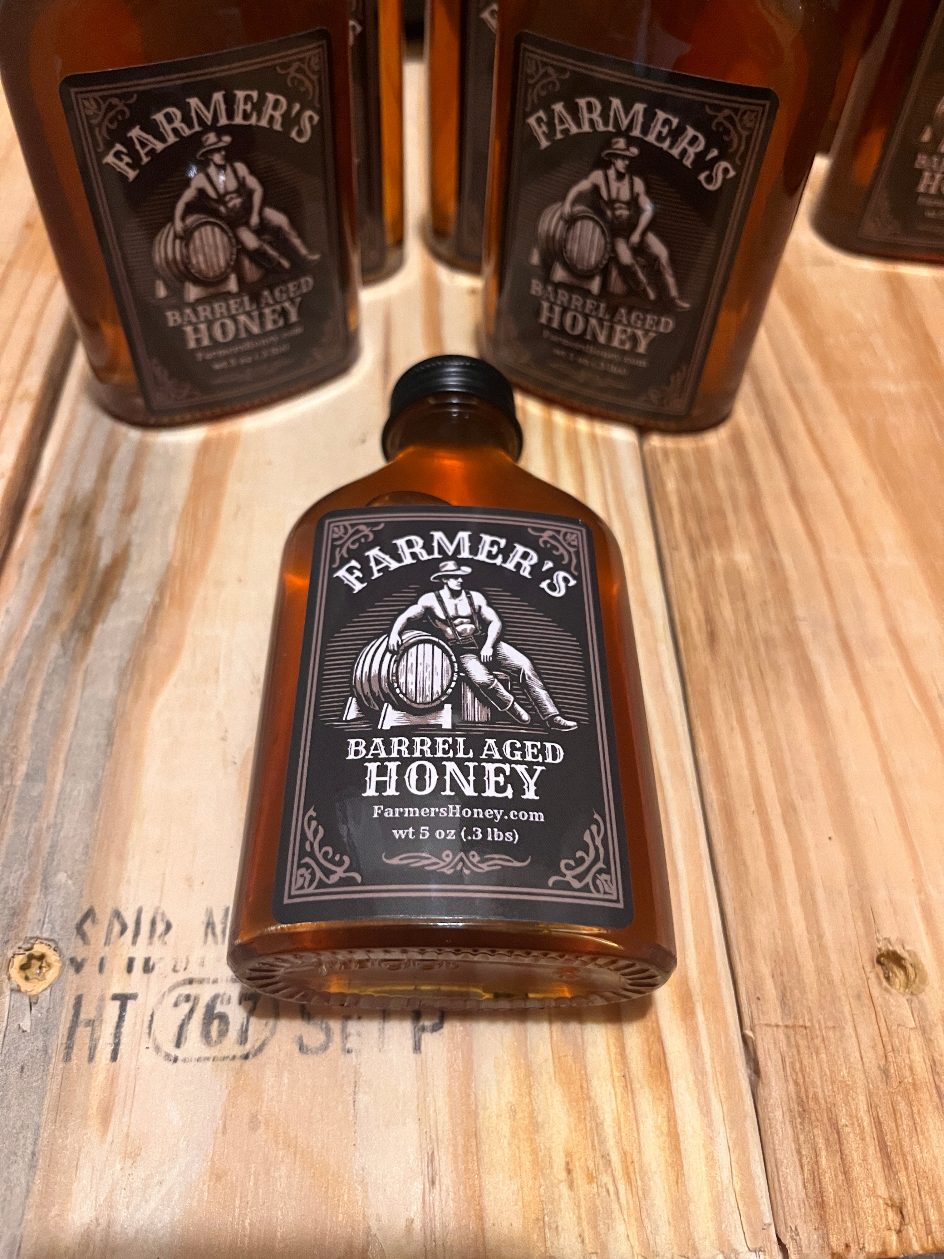 multiple bottles of farmer's barrel aged honey on a table